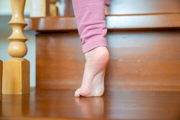 Closeup of little girl foot going up the stairs at home, child climbing stairs