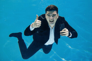 Artistic business concept. A man swims with a phone underwater on a blue background