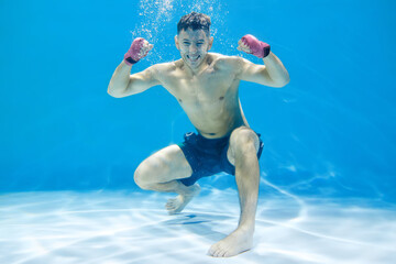 Artistic concept. Athletic man doing boxing in water on blue background