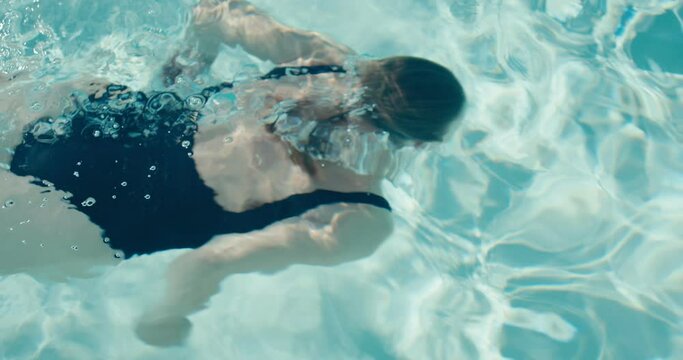 Woman swimmer underwater breaststroke swims under swimming pool water