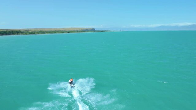 Aerial view of a man in a life jacket riding a jet ski on clear blue azure water on the sea. Sport, healthy lifestyle, outdoor recreation, vacation at sea, travel. Lake Sevan, Armenia.