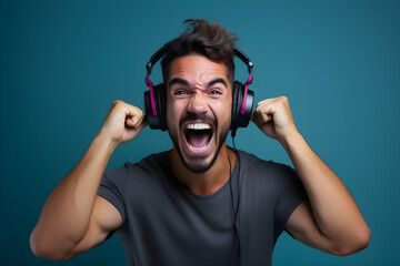 studio portrait of happy gamer man wearing headphones celebrating on blue background
 - obrazy, fototapety, plakaty
