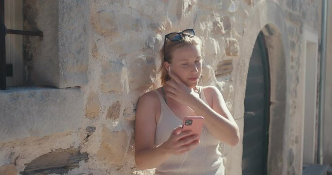 Woman tourist smartphone call talk smiles mediterranean town vacation