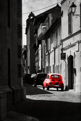 Automobile rossa parcheggiata in una via in un ambiente bianco e nero