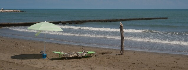 Ombrellone con sdraio lungo la spiaggia e vicino al mare