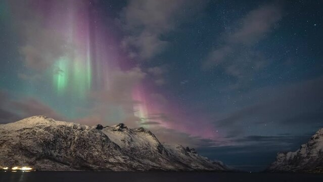 Amazing red and green aurora curtains fill a starry sky over wintery mountains in northern Norway