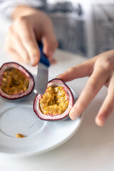 A woman cuts a passion fruit into two halves.