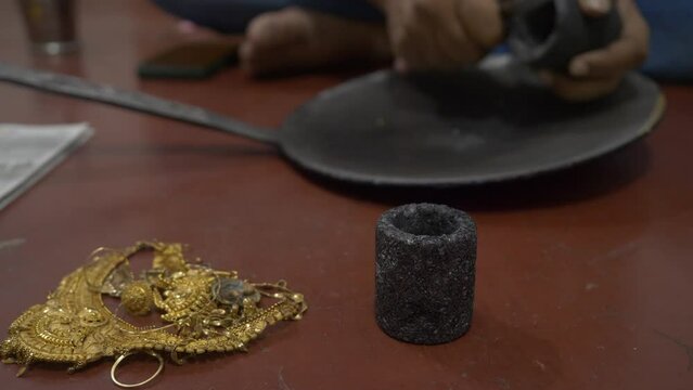 Selective focus of an Indian goldsmith preparing to melt gold jewelry in a workshop