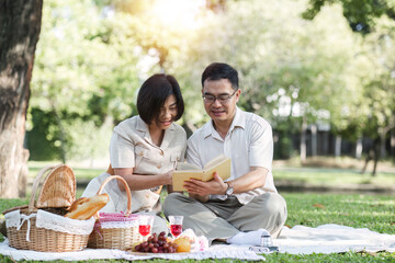 Senior couple picnicking in the park showing their love, support or reconnecting after retirement in a relaxed park. And elderly men and women happily sit on mats in the backyard to rest.