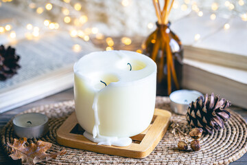 Cozy winter composition with a candle, incense sticks and bokeh lights.