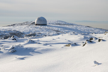 The white dome of an abandoned radar station on the top of a mountain. In the distance, small figures of people on a snow-covered mountain slope. Tourist attraction in the vicinity of Magadan. Russia. © Andrei Stepanov