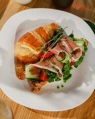 croissant sandwich with cherry tomatoes jamon and cucumber