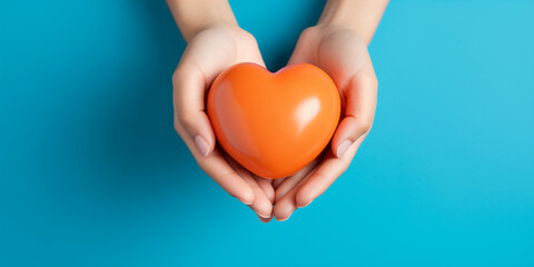 orange heart in hands on a blue background - Powered by Adobe