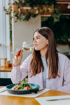 Pretty woman eating delicious dish and drinking wine during date in cafe or restaurant