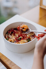Close up of woman eating Thai food of pumpkin porridge with shrimps in restaurant