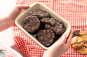 Woman holding tray with chocolate cookies, close up.