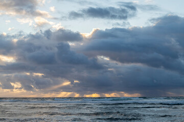 Fototapeta premium Early morning at the beach in Kauai, Hawaii, United States. the Pacific Ocean with rain clouds as the sun rises. 
