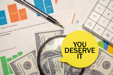 YOU DESERVE IT on yellow sticker with pen and calculator