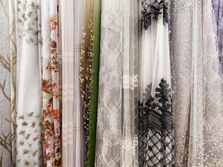 Collection of fabrics at the store counter. View of rolls of fabric in different colors and patterns in the store. Mix colorful hanging veil. Texture. background. Pattern