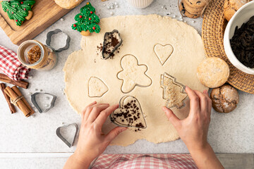 Female hands cut shapes and make Christmas cookies. - obrazy, fototapety, plakaty