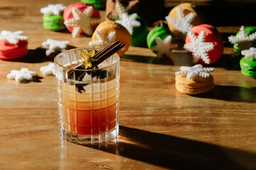 Beautiful orange Christmas cocktails with anise, cinnamon sticks and spices on wooden table. New...