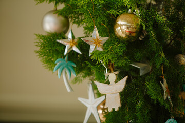 Closeup of decoration hanging on Christmas tree. Vintage wooden ornaments: stars, angels and baubles