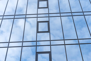 Large panoramic windows. The glass reflects the blue sky with clouds.