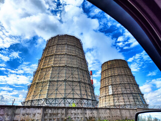 Big tower of CHPP close-up. White steam from wide pipe of CHP on blue sky. Industrial background. Huge pipes of thermal power plant produce steam for electric power. Strategically important object