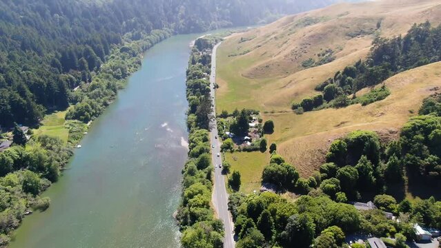 Aerial video of a country landscape with a river channel in the middle, surrounded by greenery and mountains in the horizon in Bodega Bay, Gualala coast in California.