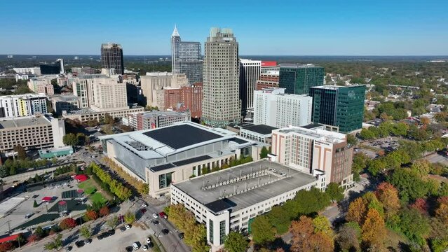 Raleigh, North Carolina skyline. Aerial orbit high above city on beautiful autumn day. Tall skyscrapers and Raleigh Convention Center.