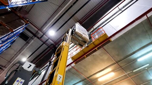 Two level warehouse. The forklift picks up a pallet from the second floor of the warehouse. Modern forklift in a warehouse