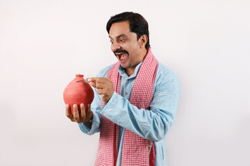 Happy Indian rural farmer man holding piggy bank in hand, Saving money and banking concepts....