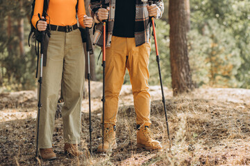 Couple hiking with bags and walking sticks in forest