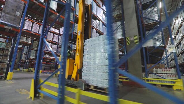 Worker on a modern forklift. Working in a large modern warehouse. Workflow in a modern warehouse