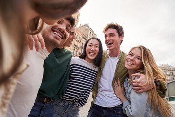 Multiracial young people team hugging together outdoor, diverse students and friends laughing. Smile happy carefree celebrating holidays. Concept unity, complicity and university community time. - obrazy, fototapety, plakaty