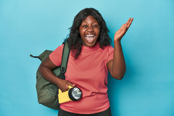 Curvy explorer with backpack and flashlight receiving a pleasant surprise, excited and raising...