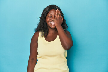 Young african american curvy woman having fun covering half of face with palm.