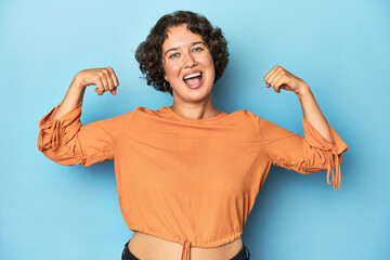 Young Caucasian woman with short hair showing strength gesture with arms, symbol of feminine power