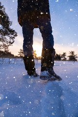 A traveler in boots walks along a snowy winter road
