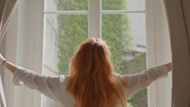 Young woman opens bedroom curtains morning routine