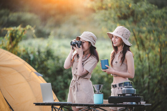 Happy woman freelancer traveller working online using laptop ,take photo and drink a cup coffee or tea enjoying the beautiful camping tent landscape with mountain is holiday relaxed lifestyle concept.