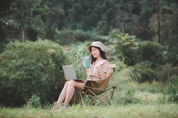 Happy woman freelancer traveller working online using laptop ,take photo and drink a cup coffee or tea enjoying the beautiful camping tent landscape with mountain is holiday relaxed lifestyle concept.