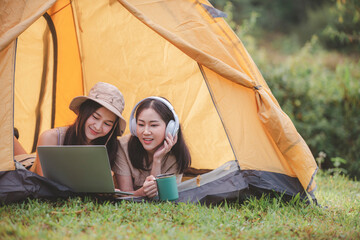 Happy woman freelancer traveller working online using laptop and drink a cup coffee or tea enjoying listen music stay in camping tent landscape with mountain is holiday relaxed lifestyle concept.