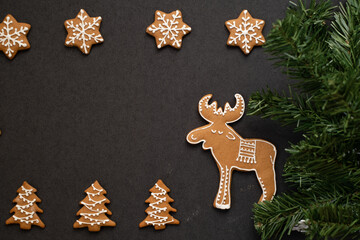 Gingerbread cookies for Christmas in the form of a moose, snowflakes and a Christmas tree. On a dark background. Pastries for Christmas and New Year