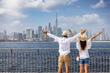 A happy tourist couple on a sightseeing tour enjoys the panoramic view of the skyline of Dubai, UAE - obrazy, fototapety, plakaty