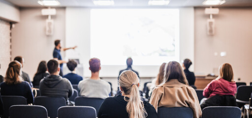 Speaker giving a talk in conference hall at business event. Rear view of unrecognizable people in audience at the conference hall. Business and entrepreneurship concept