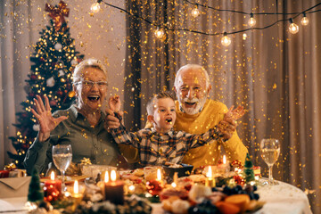 Festive grandparents celebrating new year and Christmas eve with grandson in midnight at home....