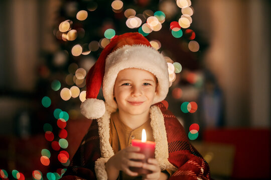 Portrait of a happy child holding a candle and smiling at the camera on christmas and new year's eve.
