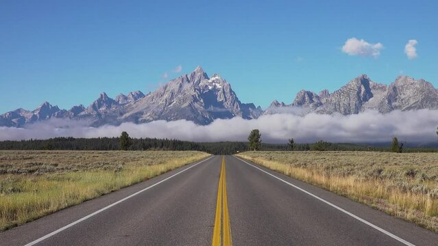 Road leads directly towards the mountains, Grand Teton National Park, Wyoming, USA