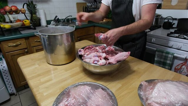 Transferrin pork bones and pig feet into large pot to be boiled for soup or broth later.